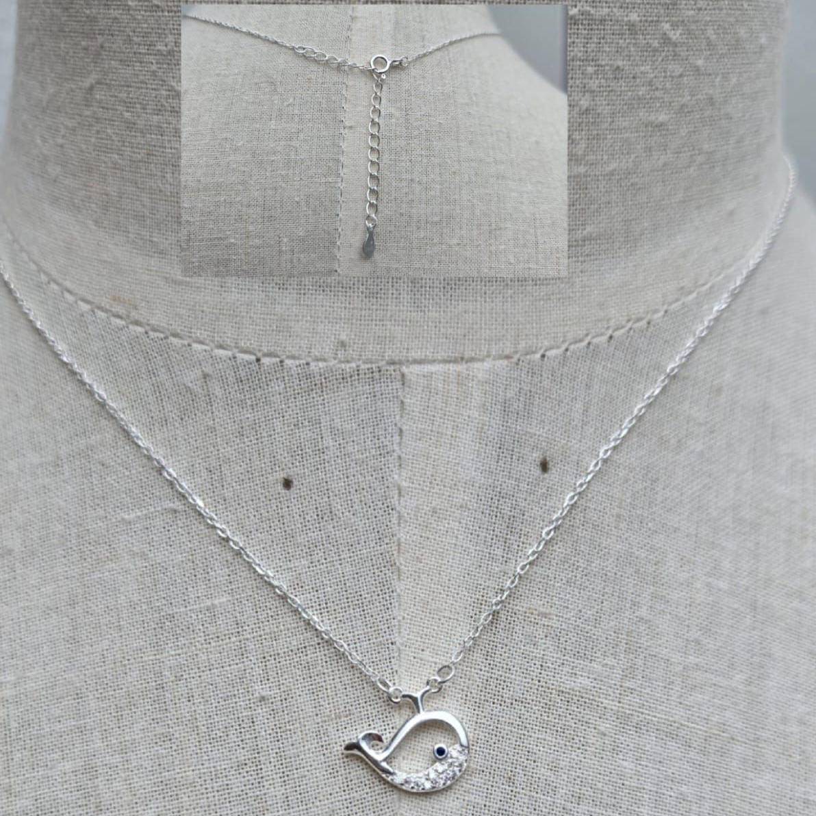 Silver necklace with a unique pendant on a mannequin.