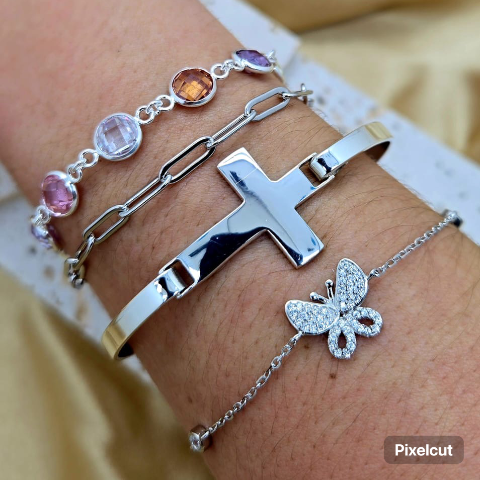 Close-up of a wrist wearing multiple silver bracelets with gemstones and a butterfly charm.