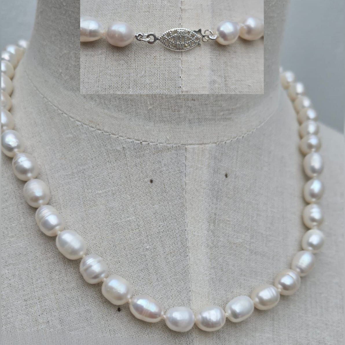 Pearl necklace on a mannequin with a close-up of the clasp on a gray background
