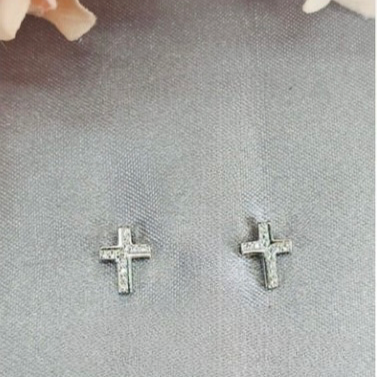 A pair of sterling silver cross studs earrings with cubic zirconia pavé, displayed against a grey background with a floral pattern.