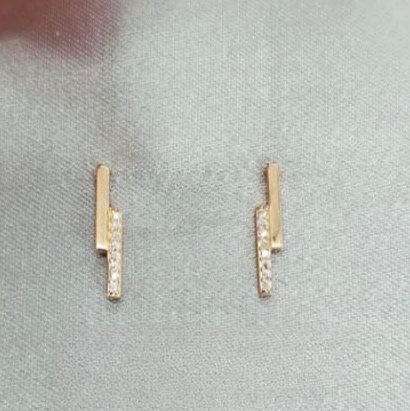 Gold bar earrings with small diamonds on a gray surface