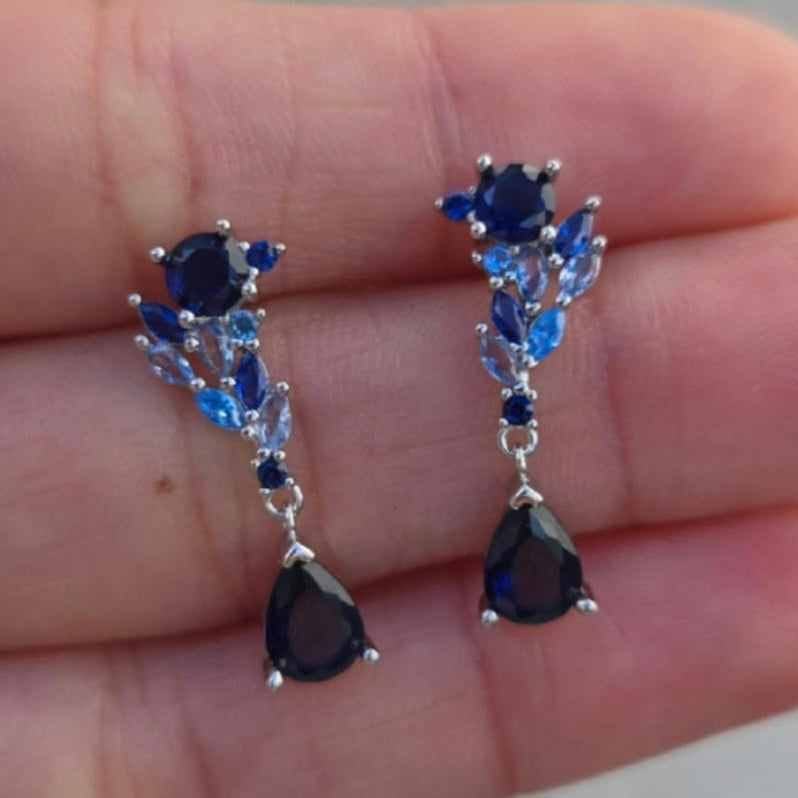 Pair of blue gemstone earrings held between fingers