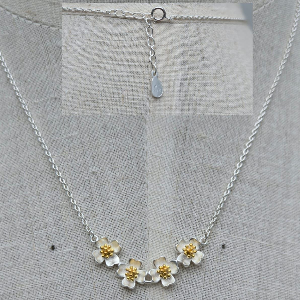 Silver necklace with floral pendants on a gray fabric background