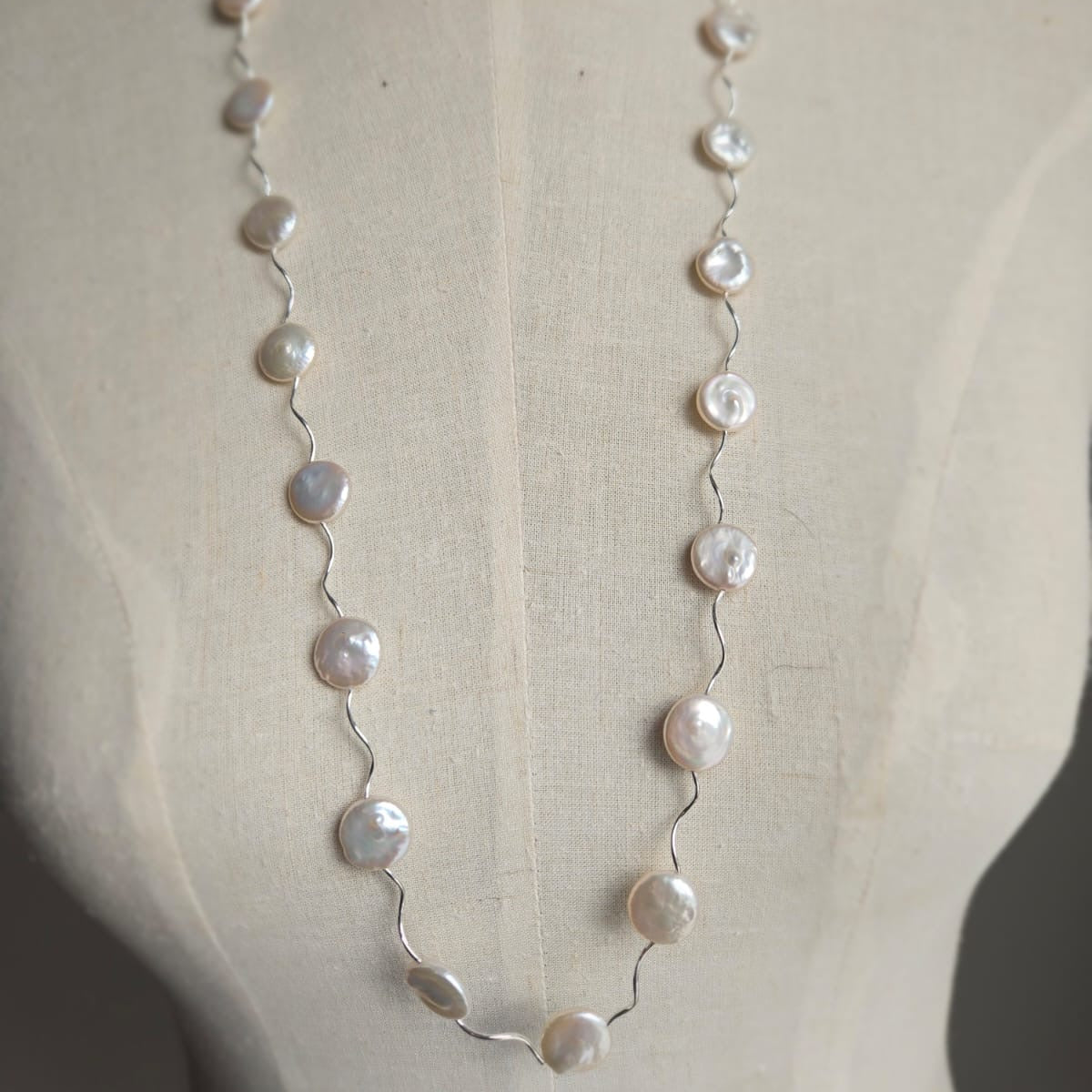 Pearl necklace on a mannequin with a plain background