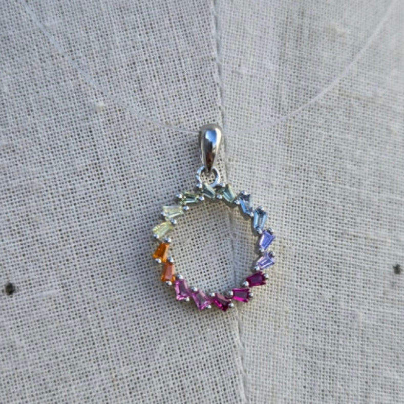 Multicolored gemstone pendant on a textured fabric background