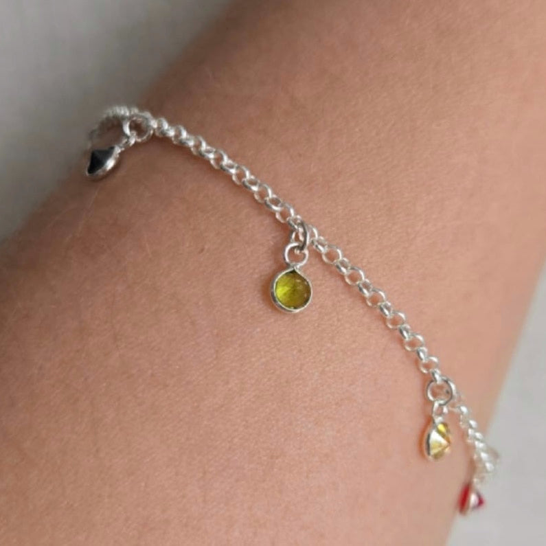 Silver anklet with yellow beads on a person's ankle against a neutral background