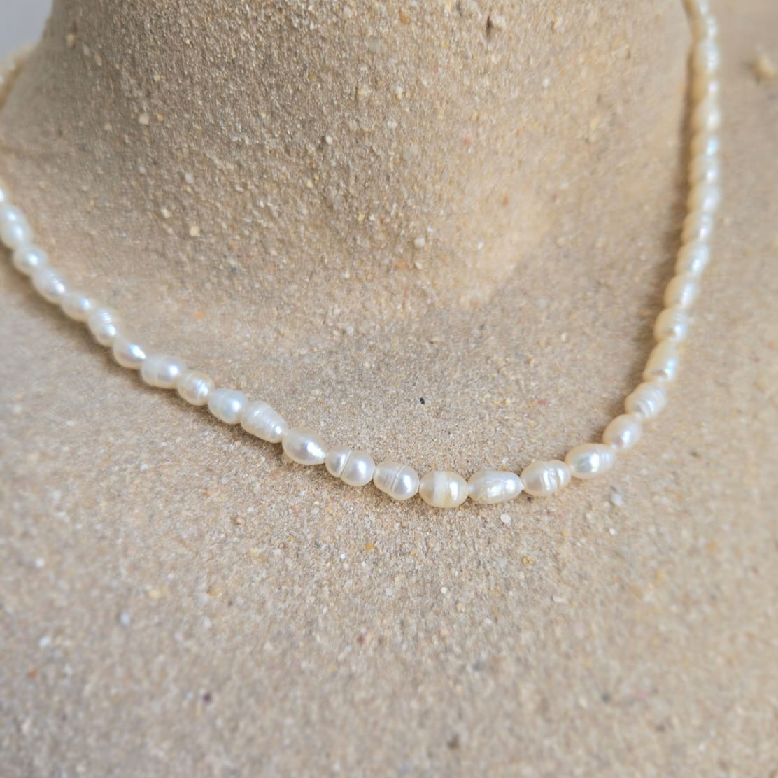 Pearl necklace on a mannequin bust with a neutral background
