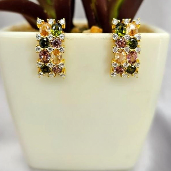 Multicolored gemstone earrings on a beige pot with a blurred background