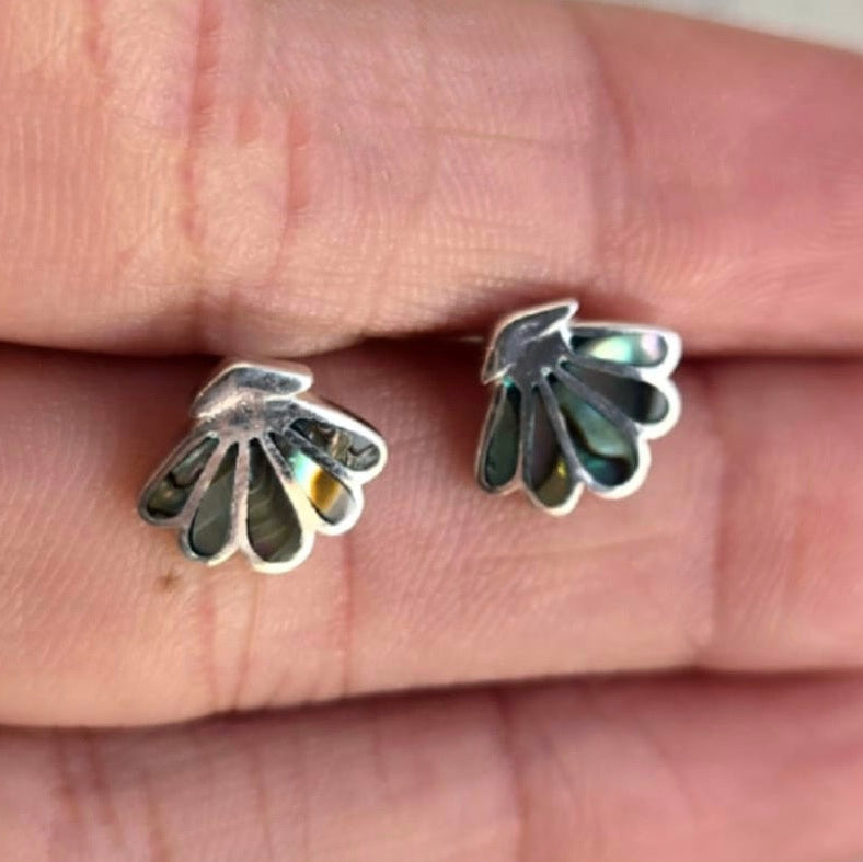 Silver leaf-shaped earrings on a person's finger