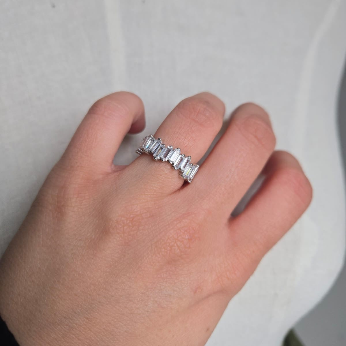Silver ring on a finger against a neutral background
