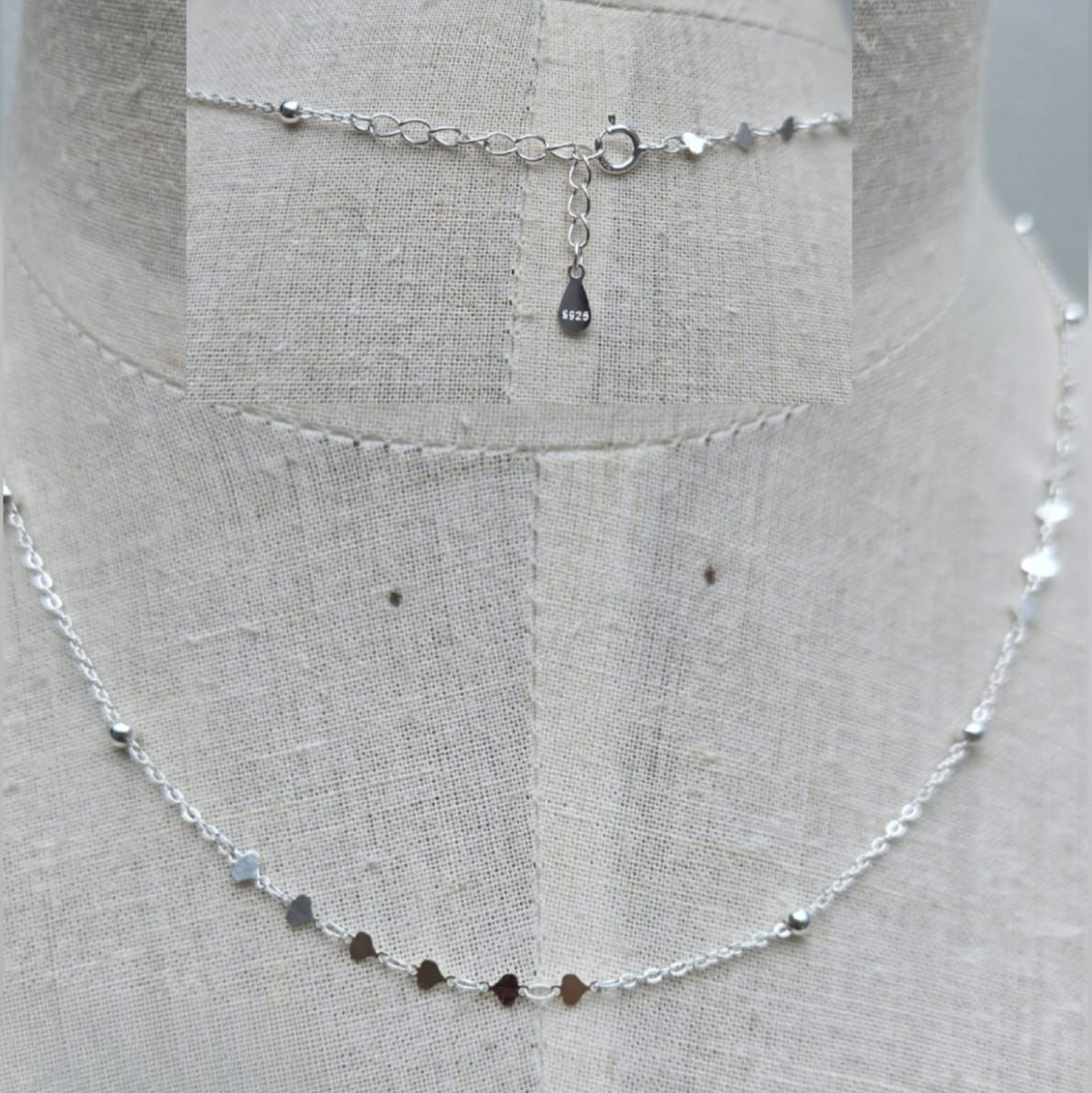 Silver beaded necklace on a mannequin with a plain background