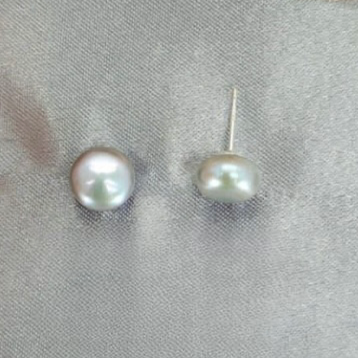 A pair of grey freshwater pearl stud earrings on a textured background.