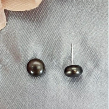A pair of dark grey/black freshwater pearl stud earrings on a textured grey background.