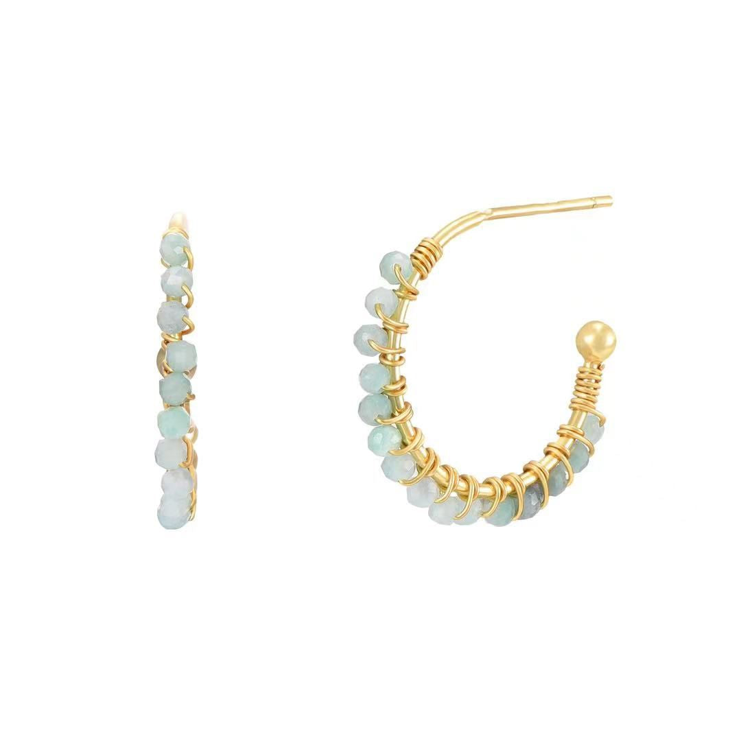 Gold hoop earrings with light blue beads on a white background