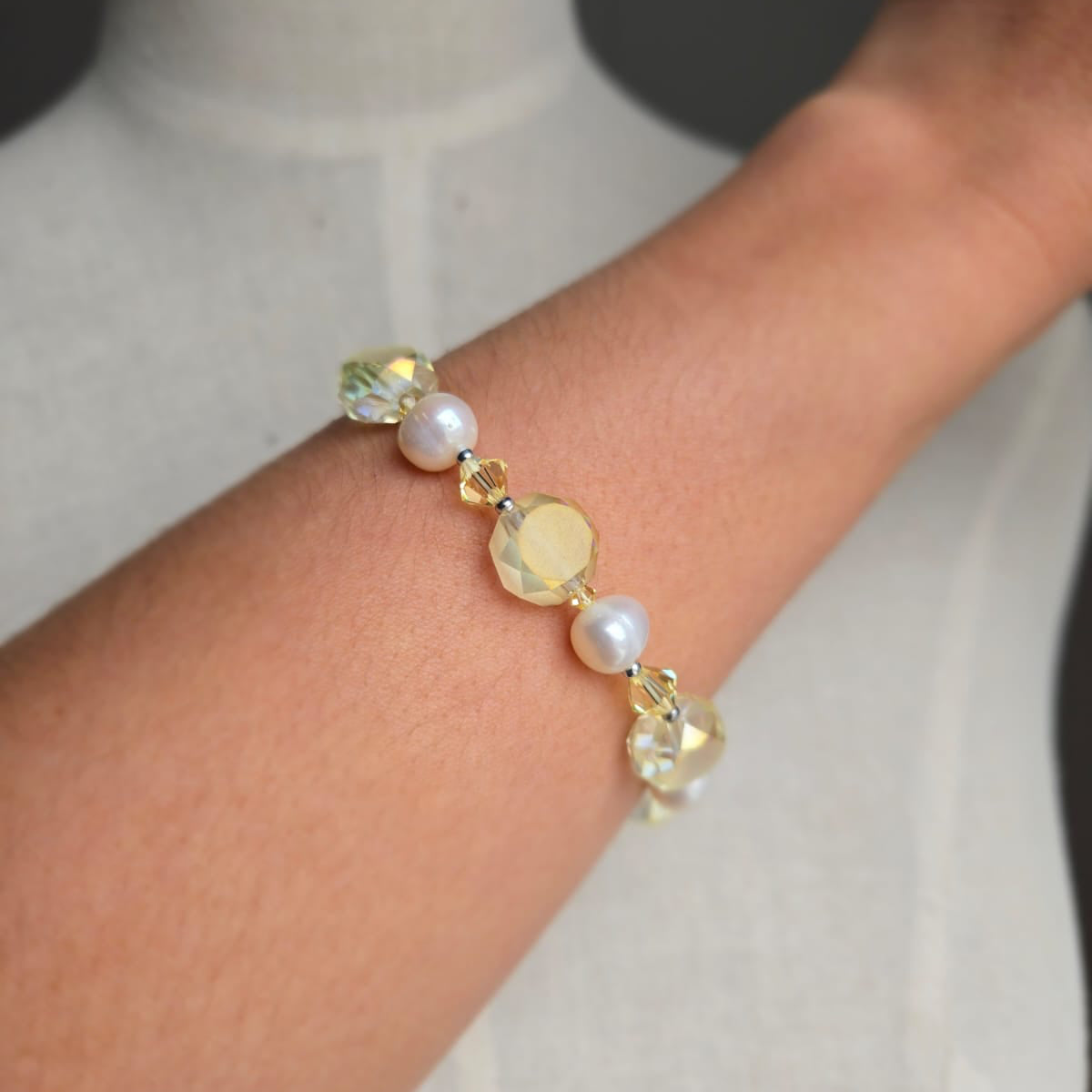 Bracelet with pearls and crystals on a wrist against a neutral background