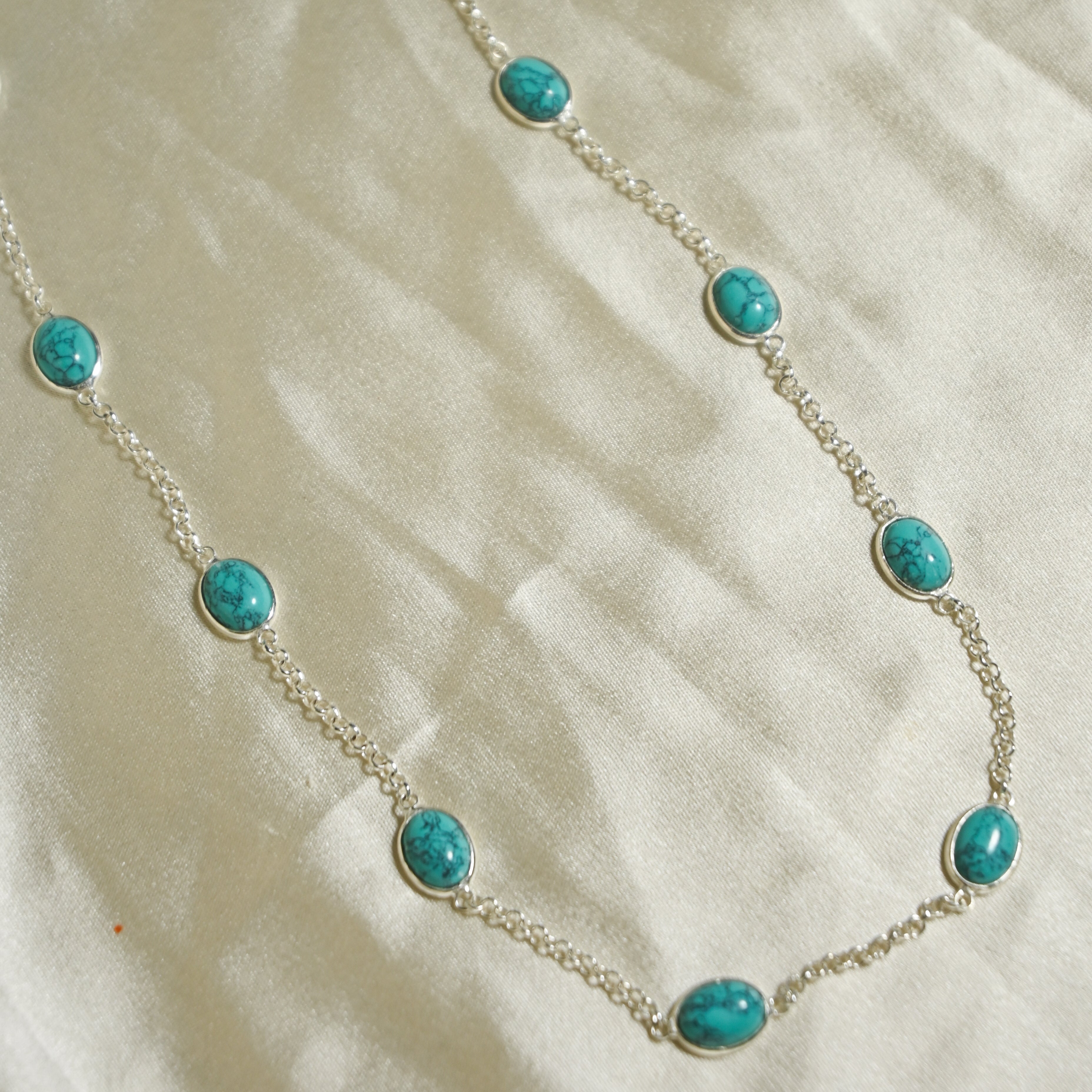 Necklace with turquoise beads on a beige fabric background