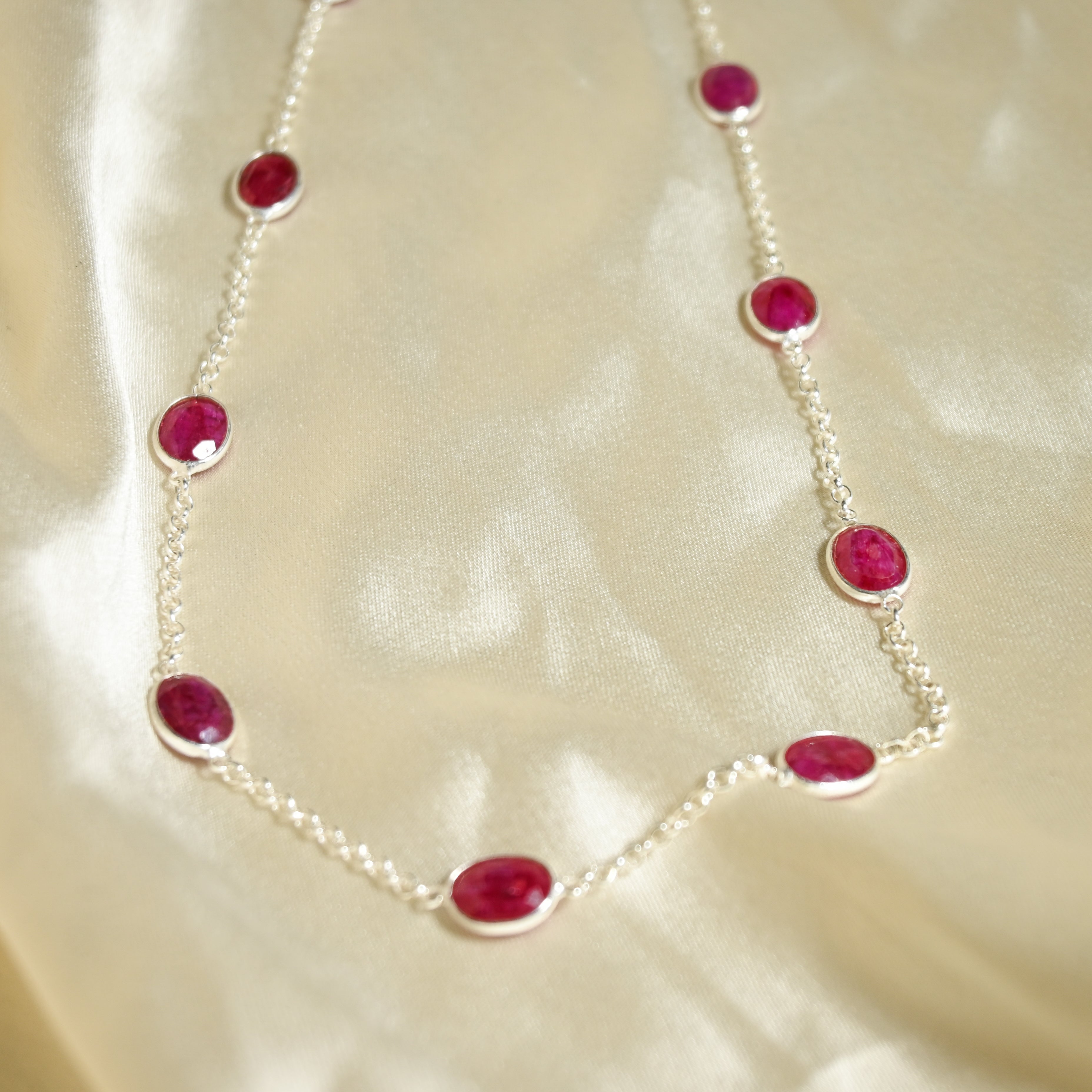 Necklace with red gemstones on a beige fabric background