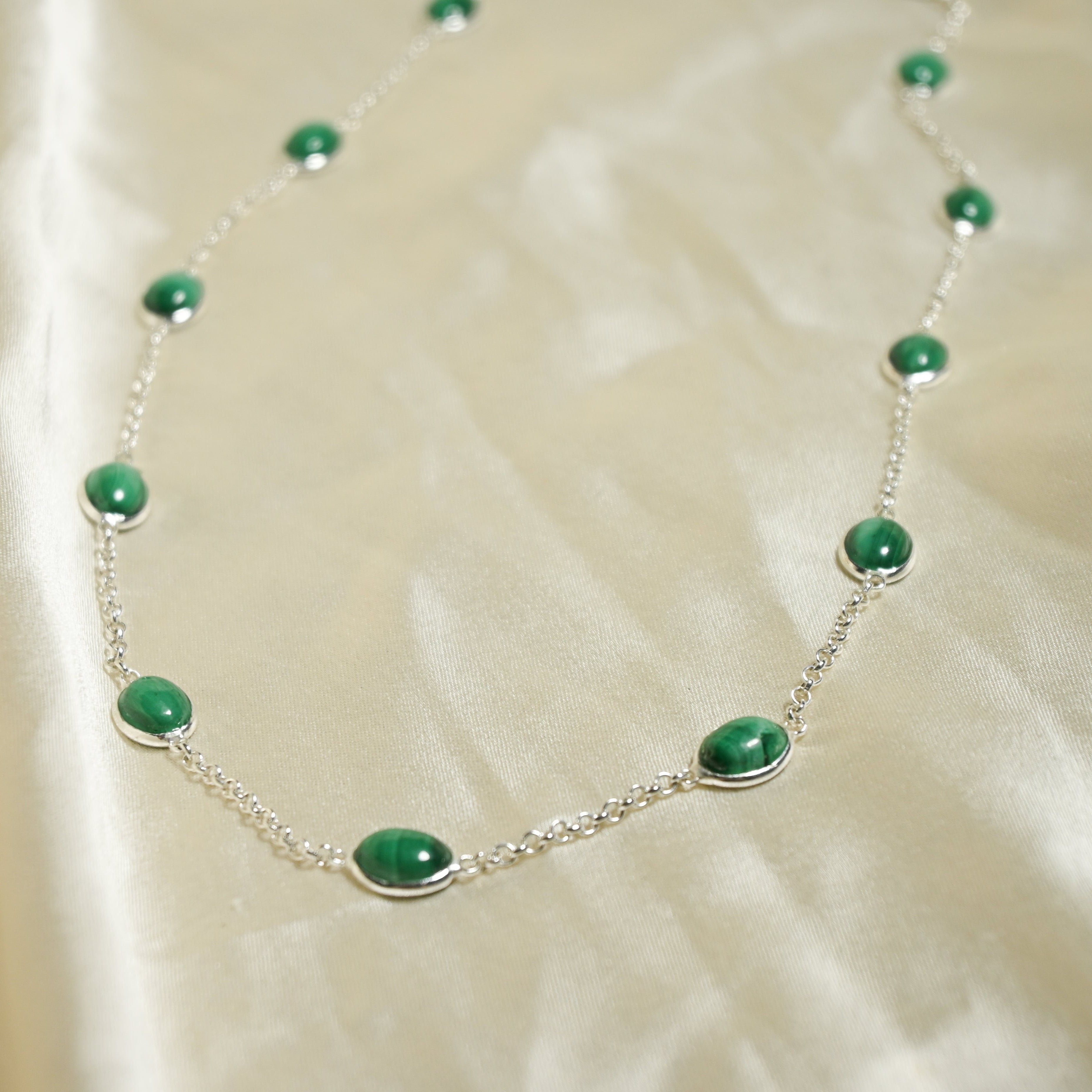 Necklace with green beads on a beige fabric background
