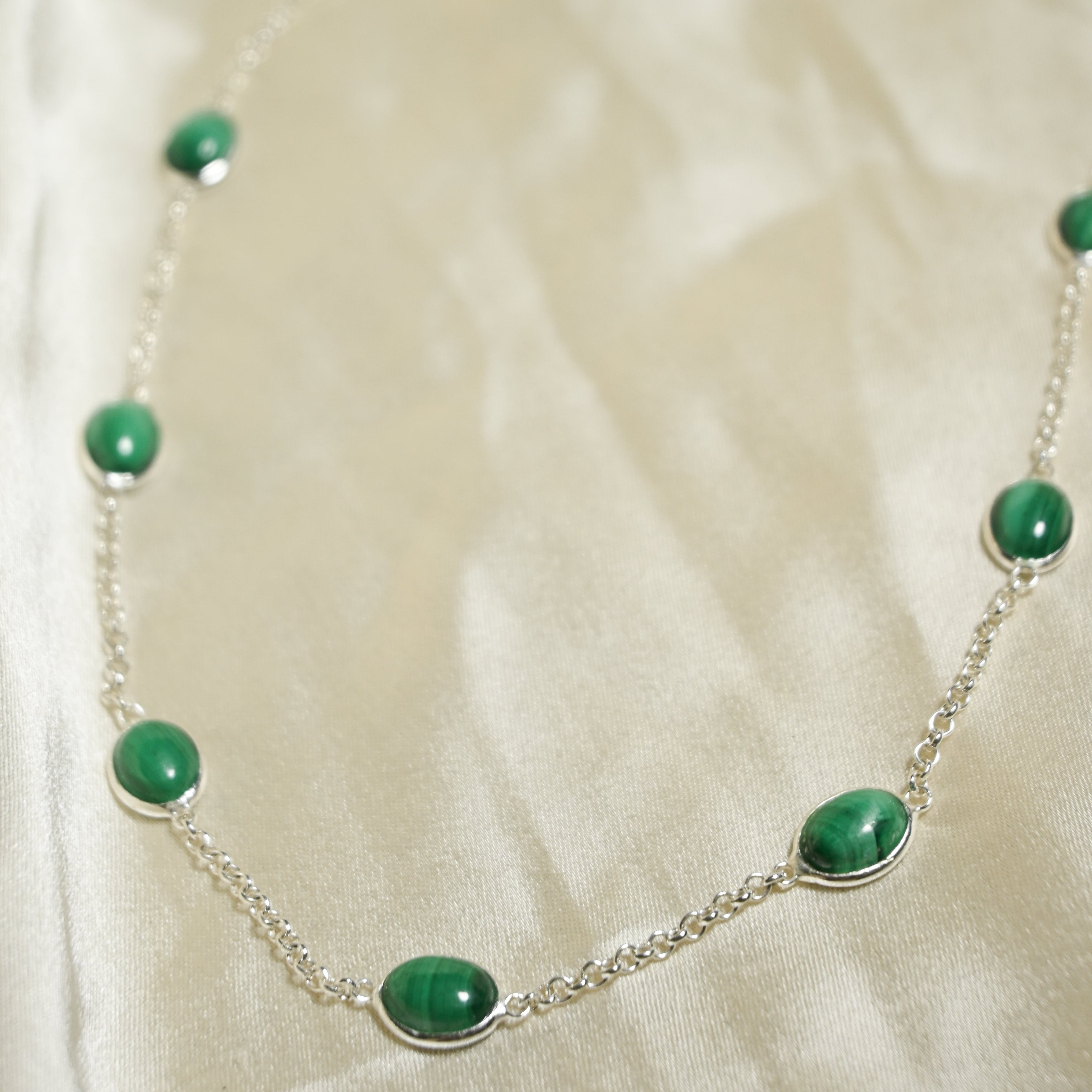 Necklace with green beads on a white fabric background