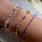 Three bracelets on a wrist against a textured surface
