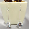 Silver earrings with clear gemstones on a neutral background