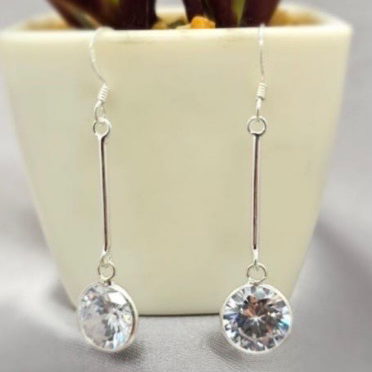 Silver earrings with clear gemstones on a neutral background