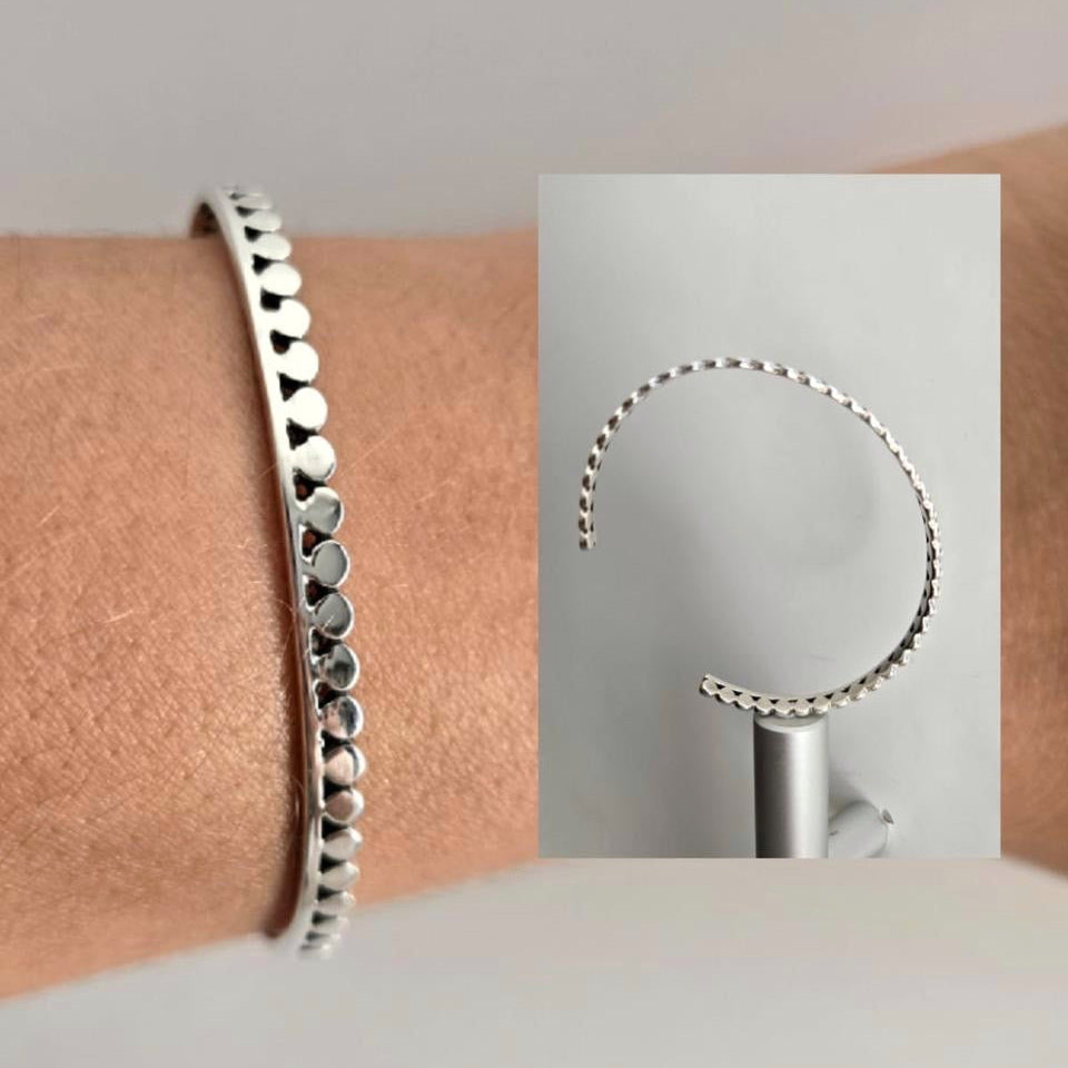 Silver beaded bracelet on a wrist with close-up inset showing bracelet details.