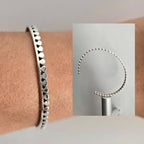 Silver beaded bracelet on a wrist with close-up inset showing bracelet details.