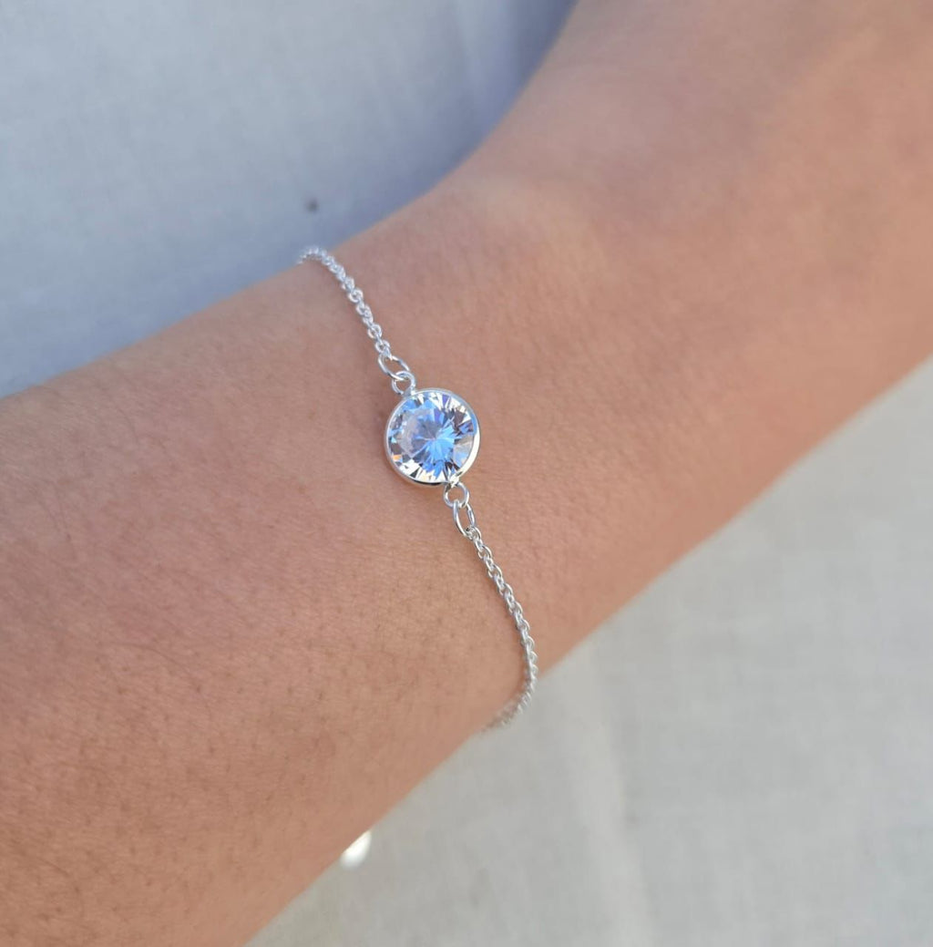 Silver bracelet with a blue gemstone on a wrist against a neutral background