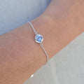 Silver bracelet with a blue gemstone on a wrist against a neutral background
