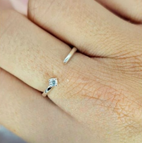 An adjustable open ring with a cubic zirconia set in sterling silver, displayed on a person's finger.