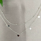 A sterling silver double necklace with a moon and star design, displayed on a textured background.