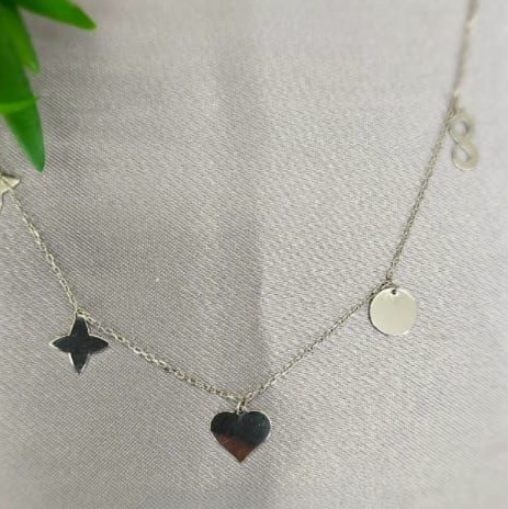 A sterling silver necklace with a series of charms including a star, a circle, and a heart, displayed against a textured background.