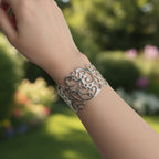 Silver decorative hair clip held in a hand against a neutral background