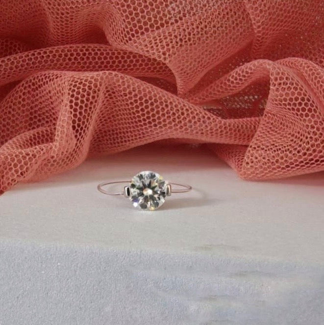 Silver ring with a diamond on a pink fabric background