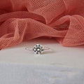 Silver ring with a diamond on a pink fabric background