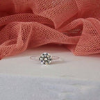 Silver ring with a diamond on a pink fabric background