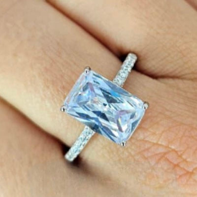 A large rectangular cubic zirconia ring with a sterling silver band, displayed on a person's finger.