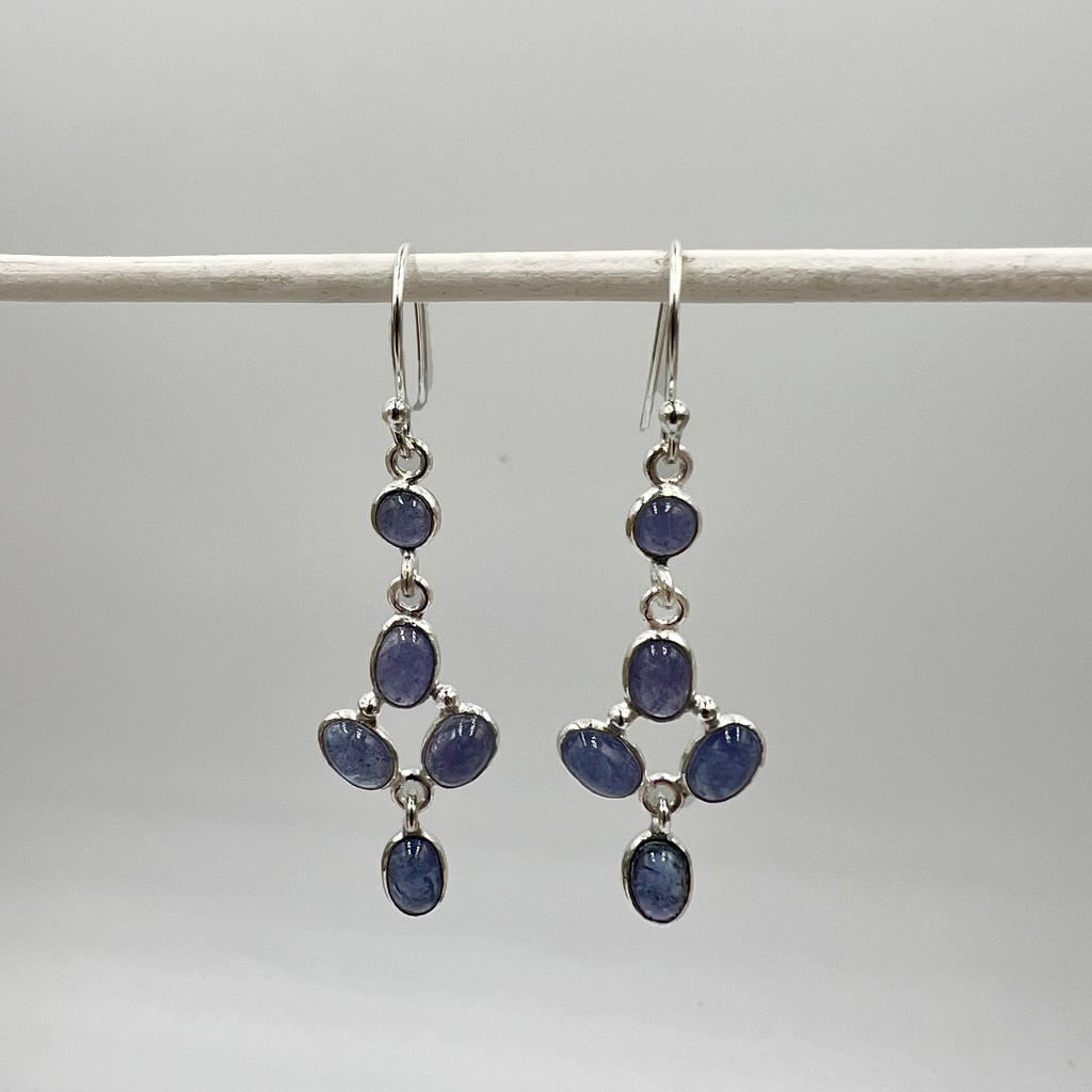 A pair of tanzanite drop earrings with silver accents, displayed against a neutral background.