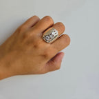 A hand wearing a sterling silver ring with five cubic zirconia stones arranged in a wave design.