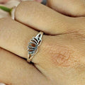 A sterling silver ring with a lotus flower design is displayed on a person's finger.
