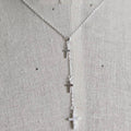 Silver cross necklace on a mannequin with a light gray background