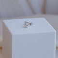 Pair of silver stud earrings on a white cube with a blurred background