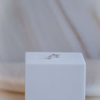 Pair of silver stud earrings on a white cube with a blurred background
