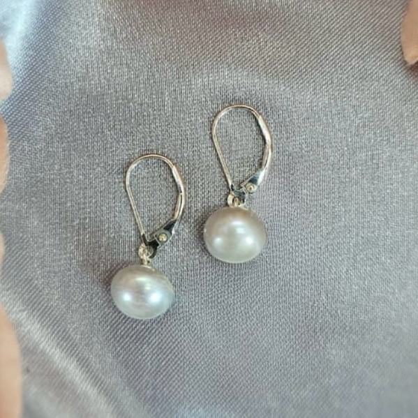 A pair of 9 mm grey drop freshwater pearl earrings with sterling silver settings, displayed on a textured fabric surface.
