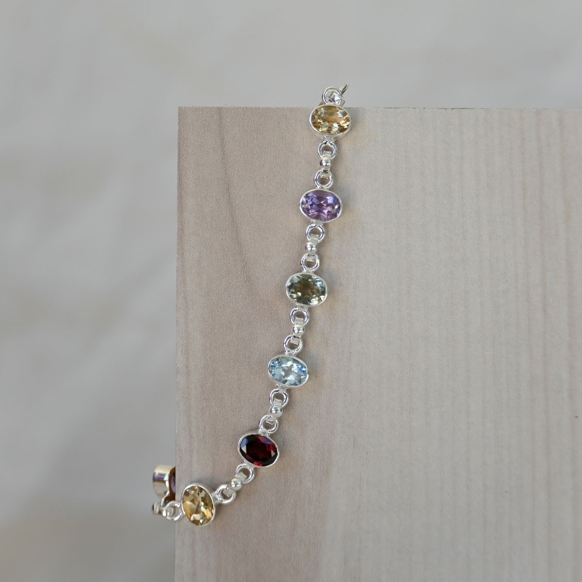 Silver bracelet with multicolored gemstones on a wooden surface