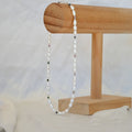 Pearl necklace on a wooden stand with a white background