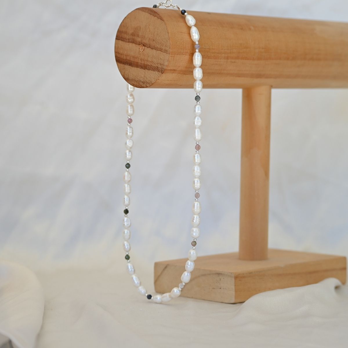 Pearl necklace on a wooden stand with a white background