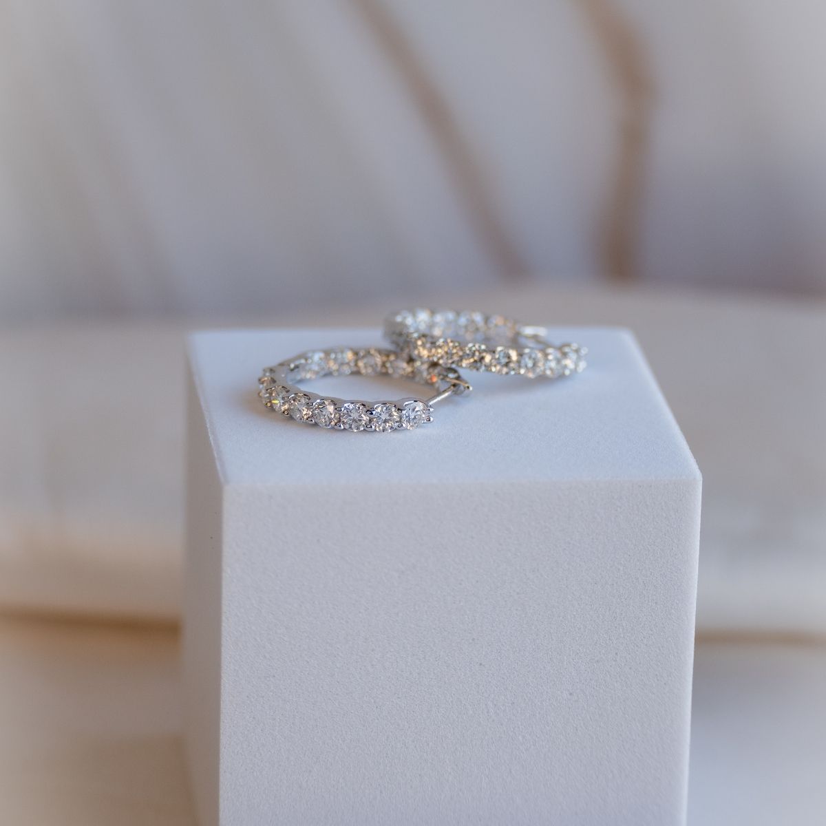 Two silver rings on a white pedestal with a blurred background