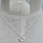 Silver necklace with a unique pendant on a mannequin.